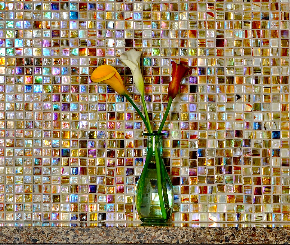 flowers in a vase next to a colorful tile wall
